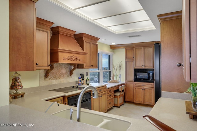 kitchen featuring custom range hood, backsplash, light countertops, black appliances, and a sink