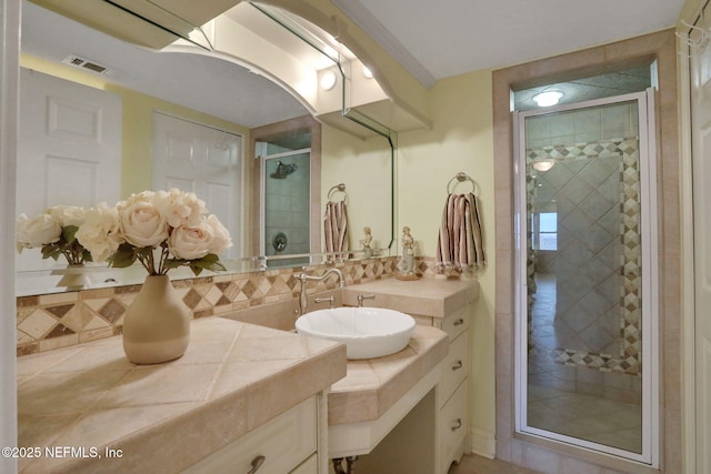 bathroom with visible vents, tasteful backsplash, a shower stall, and vanity