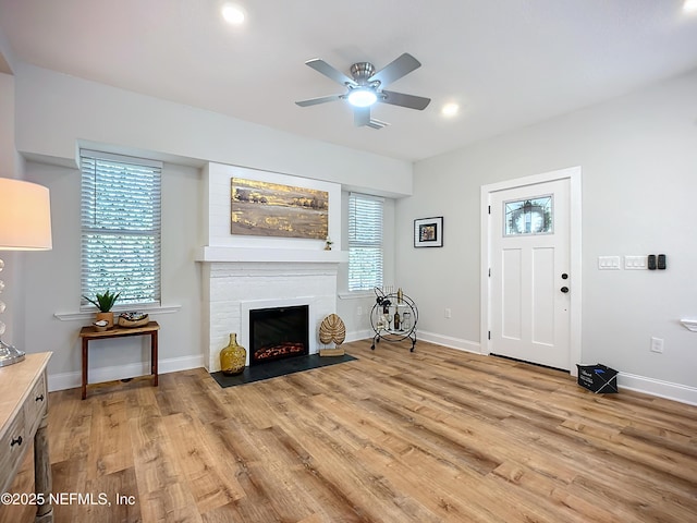 interior space with recessed lighting, light wood-style flooring, a fireplace with flush hearth, ceiling fan, and baseboards