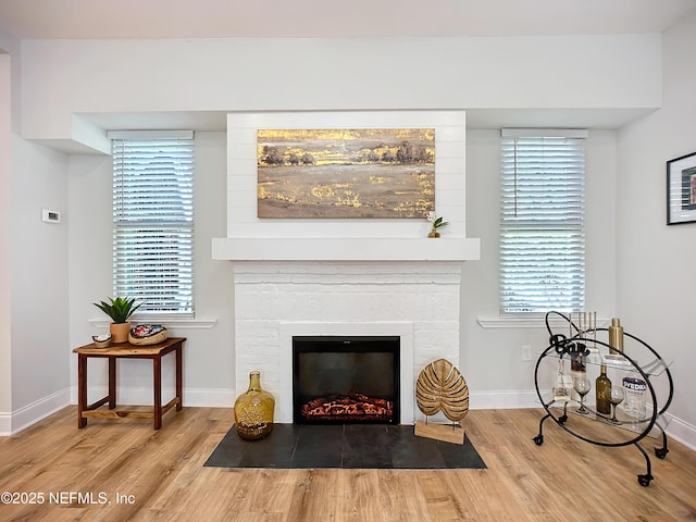 interior space featuring a fireplace with flush hearth, baseboards, and wood finished floors