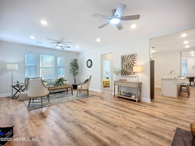 living area featuring light wood-style floors, baseboards, and recessed lighting