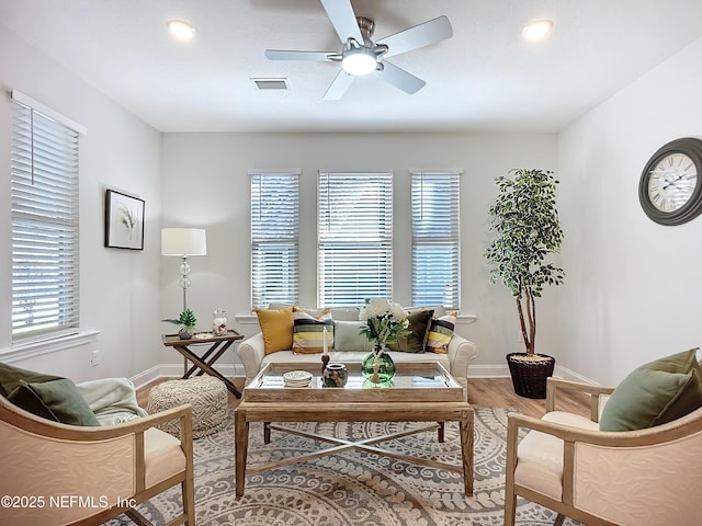 living room featuring baseboards, ceiling fan, visible vents, and wood finished floors