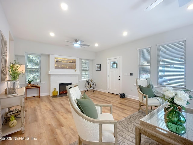 living area featuring a fireplace with flush hearth, recessed lighting, a healthy amount of sunlight, and light wood-style floors