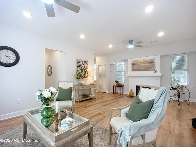 sitting room featuring a healthy amount of sunlight, a fireplace with flush hearth, light wood-style flooring, and recessed lighting