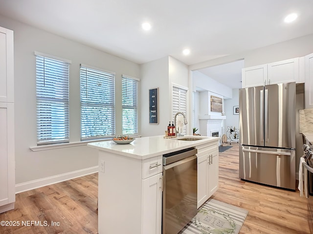 kitchen featuring appliances with stainless steel finishes, light countertops, a sink, and white cabinetry