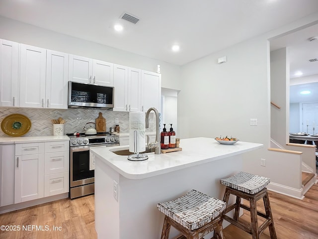 kitchen featuring visible vents, white cabinets, appliances with stainless steel finishes, light countertops, and a sink