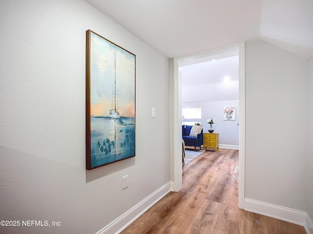 corridor with vaulted ceiling, wood finished floors, and baseboards