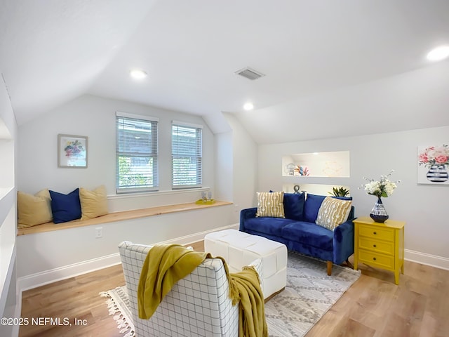 living room with light wood-style flooring, visible vents, vaulted ceiling, and baseboards