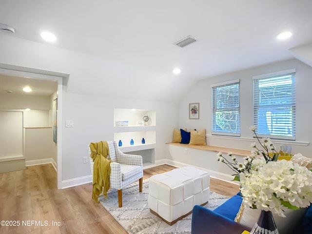 sitting room featuring lofted ceiling, light wood-type flooring, visible vents, and baseboards