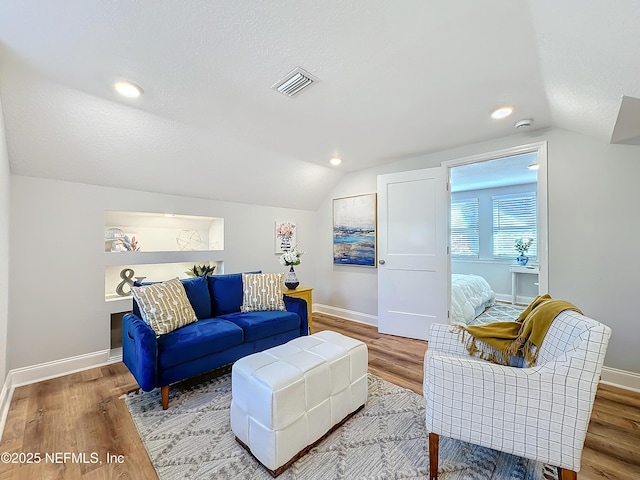 living room with lofted ceiling, wood finished floors, and visible vents