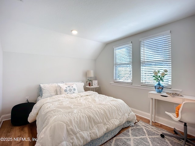 bedroom featuring lofted ceiling, baseboards, and wood finished floors