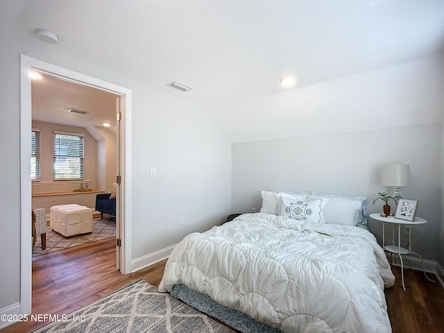 bedroom with baseboards, visible vents, vaulted ceiling, and dark wood-type flooring