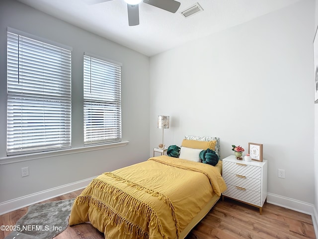 bedroom with visible vents, ceiling fan, baseboards, and wood finished floors