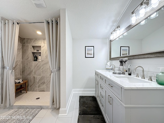 bathroom with a stall shower, a sink, a textured ceiling, and double vanity