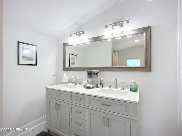 bathroom featuring vaulted ceiling, a sink, and double vanity