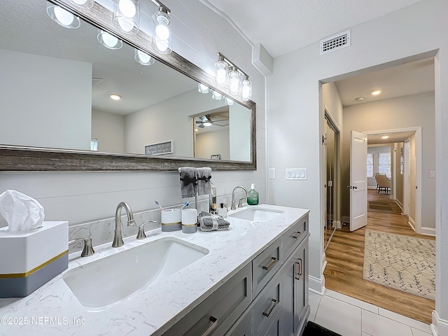 bathroom with double vanity, wood finished floors, a sink, and visible vents