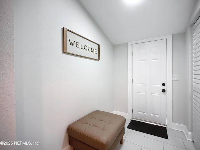 doorway with light tile patterned floors and baseboards