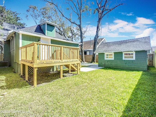 back of house featuring a yard, roof with shingles, fence, and a wooden deck