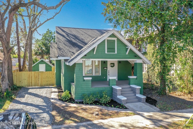 view of front of house featuring a porch, roof with shingles, and fence