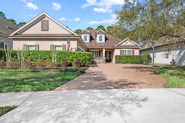 view of front of property featuring a front yard, decorative driveway, and stucco siding