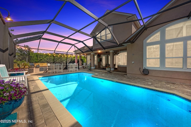 pool with glass enclosure, area for grilling, outdoor dining area, and a patio area