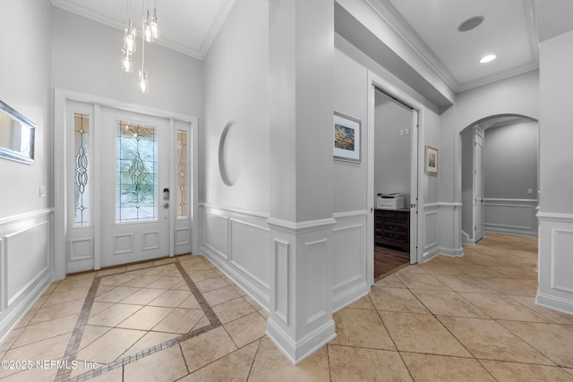 foyer entrance with a decorative wall, recessed lighting, arched walkways, and ornamental molding