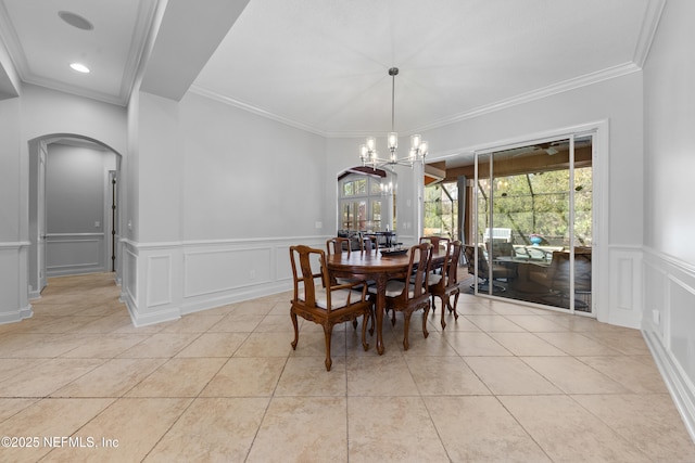 dining space featuring arched walkways, an inviting chandelier, crown molding, a decorative wall, and light tile patterned floors