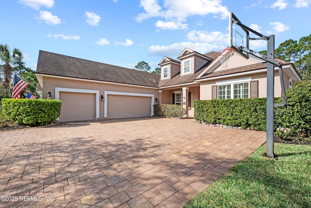 view of front of home with stucco siding, decorative driveway, and an attached garage