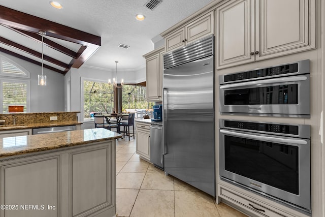 kitchen featuring a chandelier, cream cabinets, light tile patterned flooring, hanging light fixtures, and stainless steel appliances