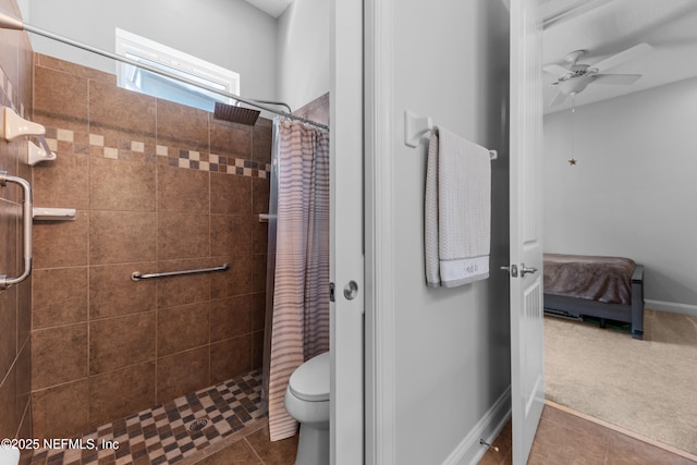 bathroom featuring baseboards, toilet, a stall shower, tile patterned floors, and a ceiling fan