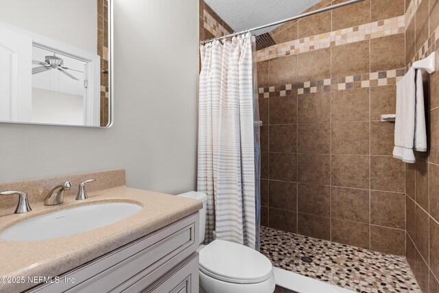 bathroom featuring a shower stall, toilet, vanity, and ceiling fan