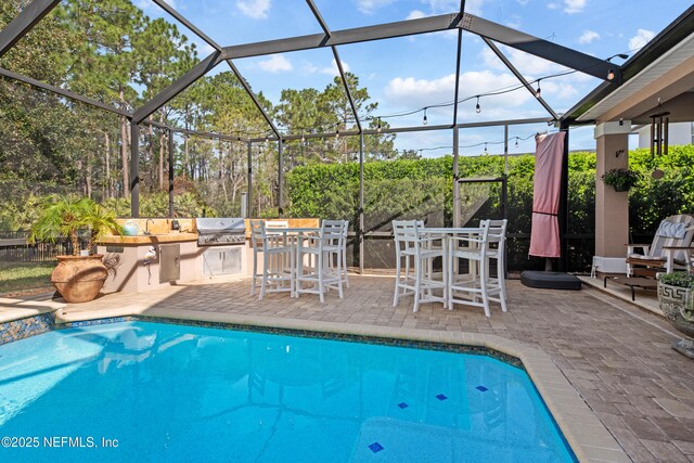 pool featuring outdoor dry bar, outdoor dining area, an outdoor kitchen, a grill, and a patio