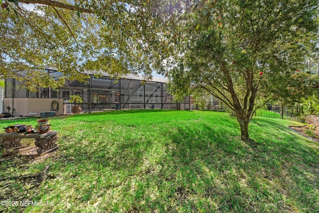 view of yard with glass enclosure and fence