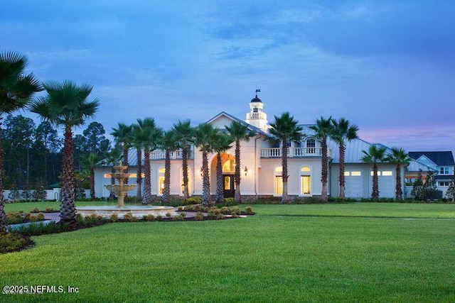 mediterranean / spanish house with a balcony, an attached garage, and a front lawn