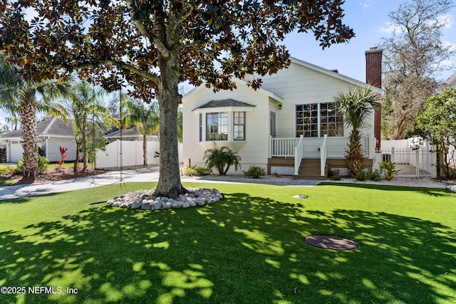 view of front of property with a chimney, a front yard, and fence