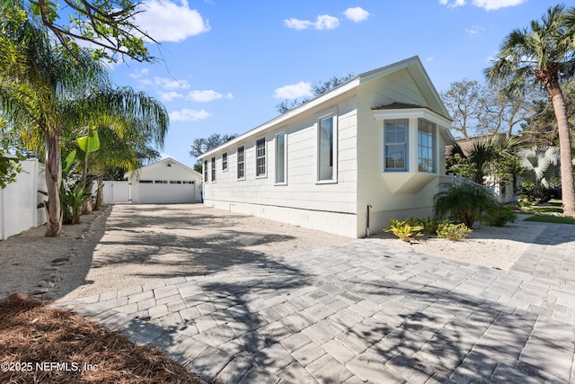 view of property exterior with crawl space, a detached garage, an outdoor structure, and fence