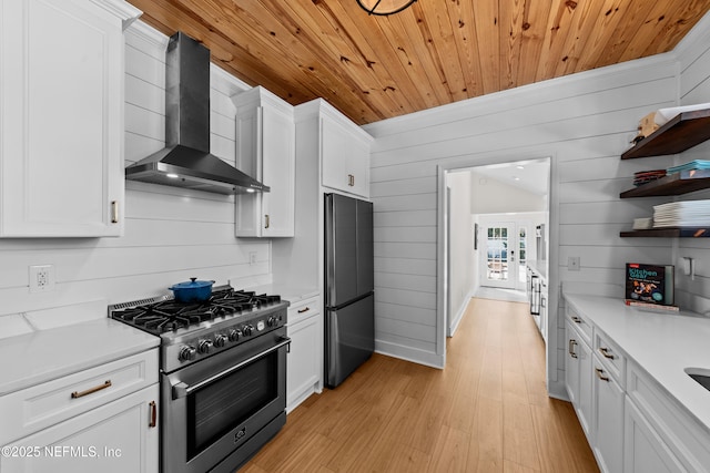 kitchen featuring open shelves, wall chimney range hood, light countertops, and appliances with stainless steel finishes