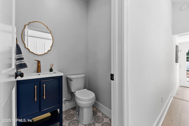 bathroom with toilet, vanity, baseboards, and wood finished floors