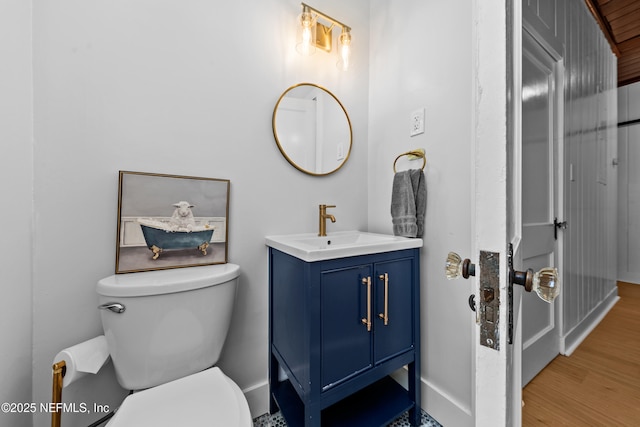 bathroom with toilet, vanity, baseboards, and wood finished floors