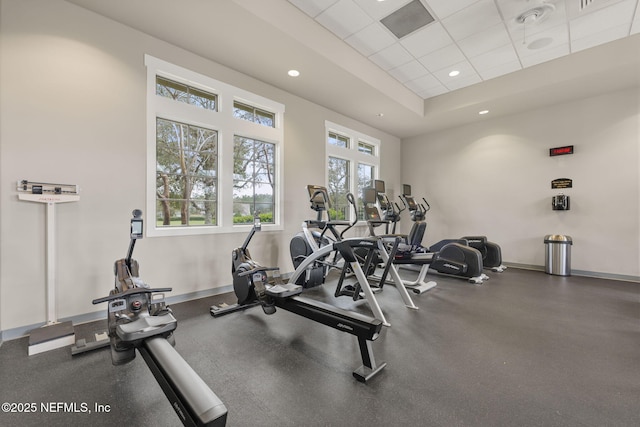 gym featuring baseboards, a raised ceiling, a drop ceiling, and recessed lighting