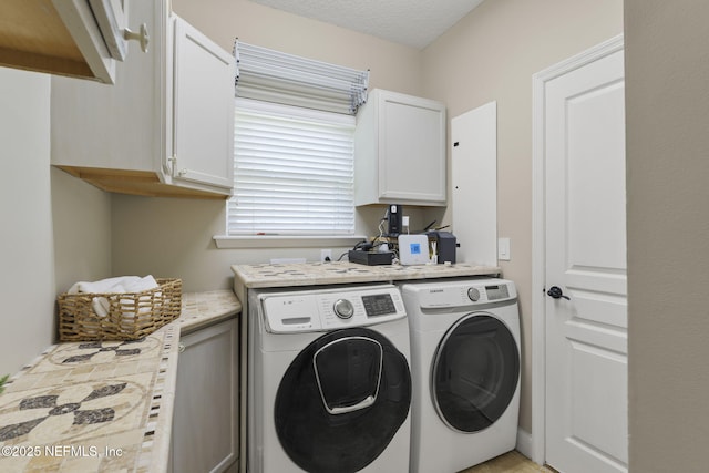 clothes washing area with cabinet space, a textured ceiling, and separate washer and dryer