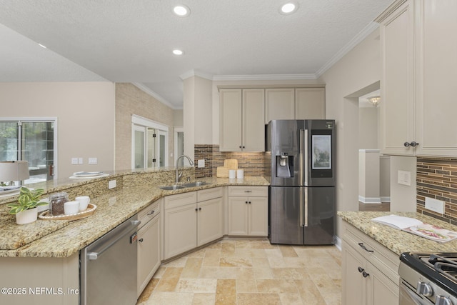 kitchen featuring light stone counters, stainless steel appliances, a peninsula, a sink, and decorative backsplash