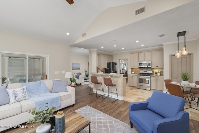 living room with light wood-type flooring, visible vents, crown molding, and lofted ceiling