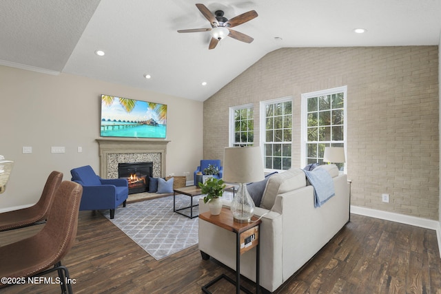 living room with lofted ceiling, a fireplace, brick wall, and wood finished floors