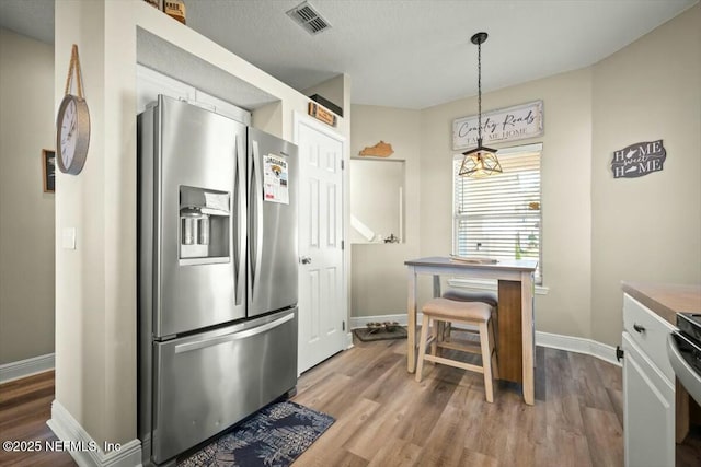 kitchen featuring baseboards, visible vents, stainless steel refrigerator with ice dispenser, and wood finished floors