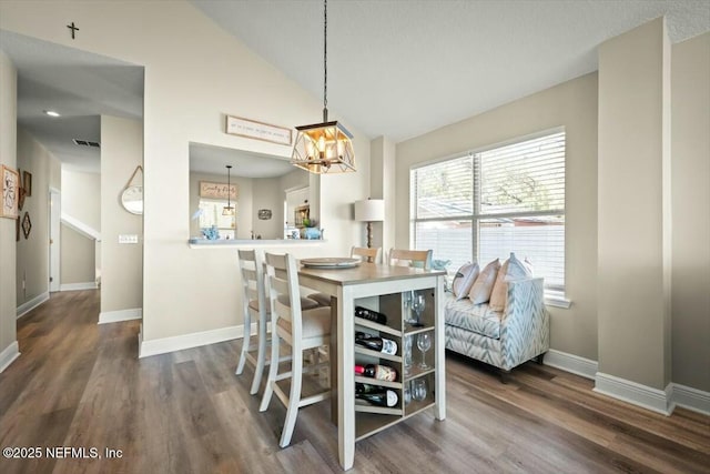 dining room with visible vents, baseboards, dark wood-type flooring, an inviting chandelier, and vaulted ceiling