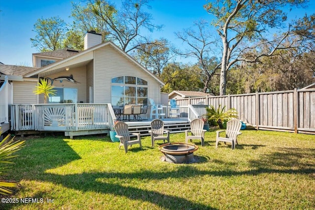 back of property featuring an outdoor fire pit, a lawn, a chimney, fence, and a wooden deck