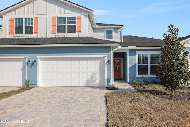 view of front facade featuring board and batten siding, decorative driveway, roof with shingles, and a garage