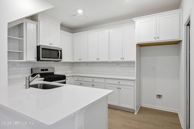 kitchen with stainless steel appliances, backsplash, light countertops, and white cabinetry