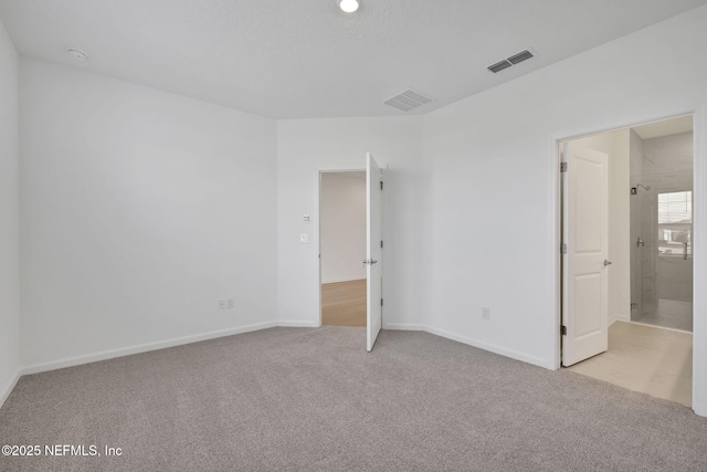 unfurnished bedroom with light carpet, connected bathroom, visible vents, and baseboards